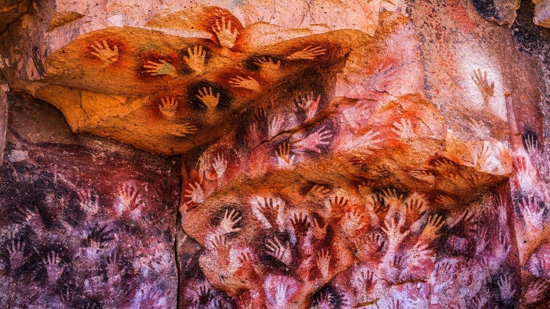 The numerous hand stencils of Cueva de las Manos, Argentina. The hand prints of many different people separated by hundreds or thousands of years, their stories lost to time but their art
